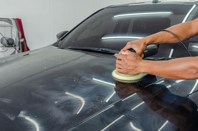 Mechaniker poliert die Karosserie eines Autos
